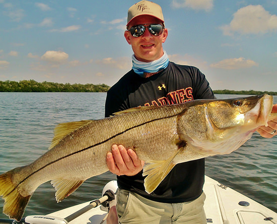 Young man holding large snook caught on a fishing charter with Florida Inshore Xtream Fishing Charters, Boca Grande, Englewood and Pine Island Sound