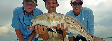 Smiling young man holding large fish.